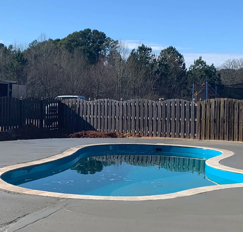 Concrete pool deck surrounding a backyard swimming pool in Meridianville, Alabama