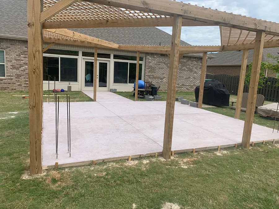 Concrete patio slab poured beneath a wood pergola at a North Alabama home